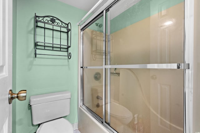 bathroom with combined bath / shower with glass door and toilet