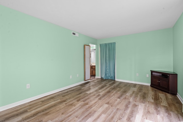 unfurnished bedroom with ensuite bathroom and light hardwood / wood-style flooring