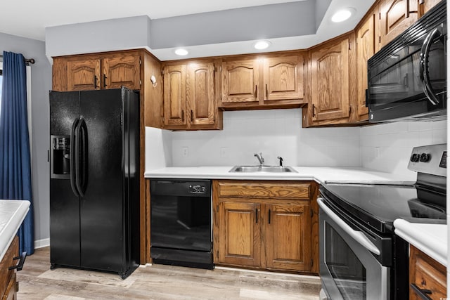 kitchen featuring decorative backsplash, sink, black appliances, and light hardwood / wood-style flooring