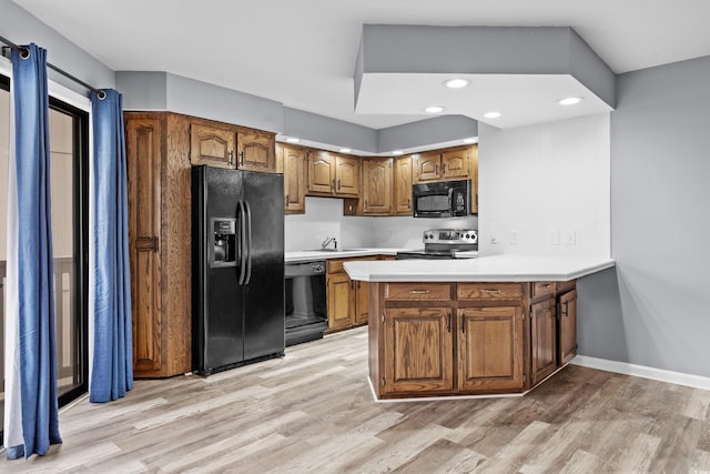 kitchen featuring black appliances, kitchen peninsula, sink, and light hardwood / wood-style flooring