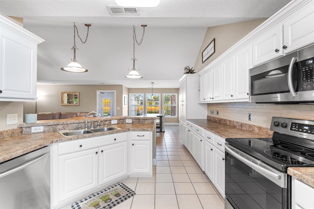 kitchen featuring light tile patterned flooring, a peninsula, a sink, white cabinets, and appliances with stainless steel finishes