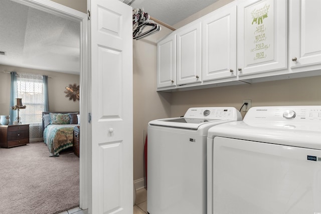 laundry room featuring washing machine and clothes dryer, light colored carpet, visible vents, cabinet space, and a textured ceiling