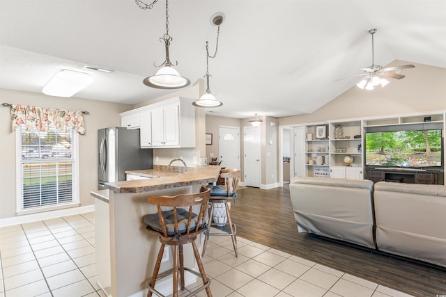 kitchen featuring light tile patterned floors, white cabinets, a breakfast bar area, open floor plan, and stainless steel refrigerator with ice dispenser