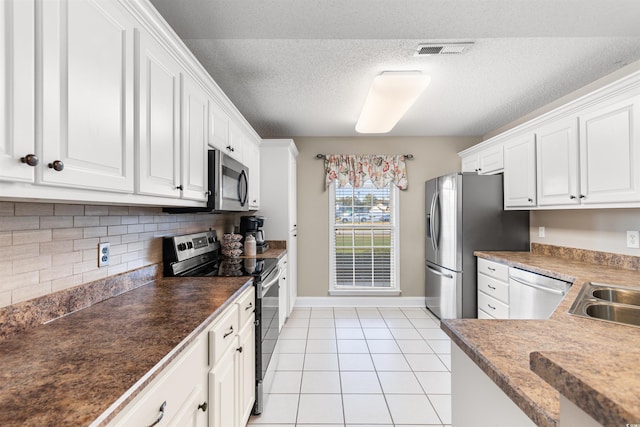 kitchen featuring light tile patterned floors, stainless steel appliances, visible vents, white cabinetry, and backsplash