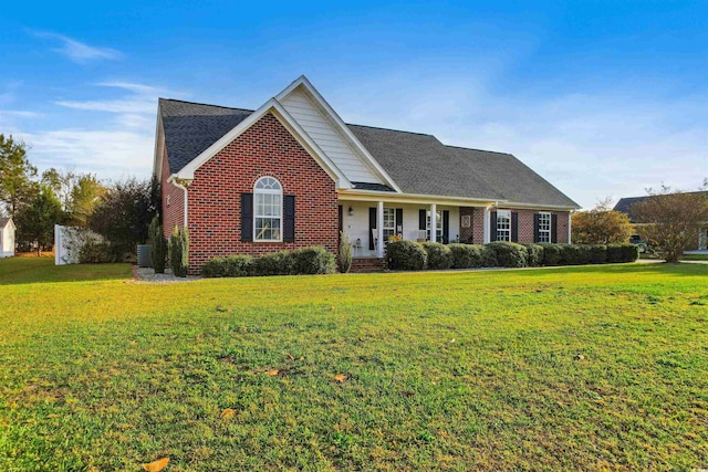 traditional-style house featuring a shingled roof, a front lawn, and brick siding