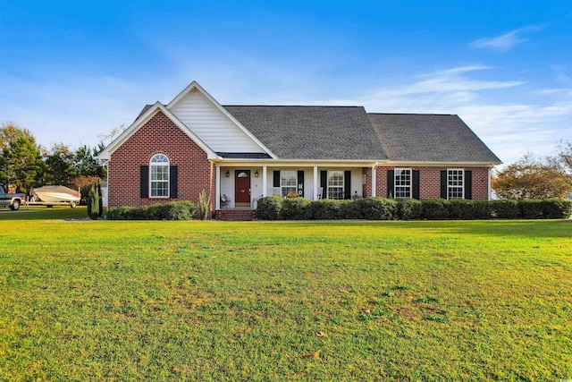 traditional home featuring roof with shingles, a front yard, and brick siding