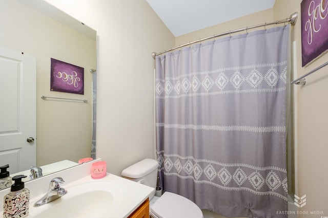 bathroom with vanity, toilet, curtained shower, and lofted ceiling