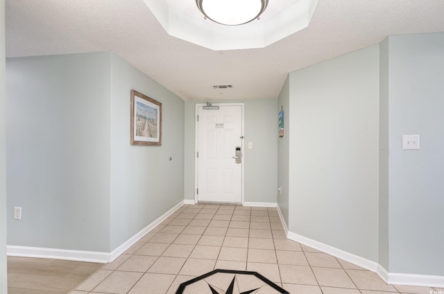 corridor featuring light tile patterned floors and a textured ceiling