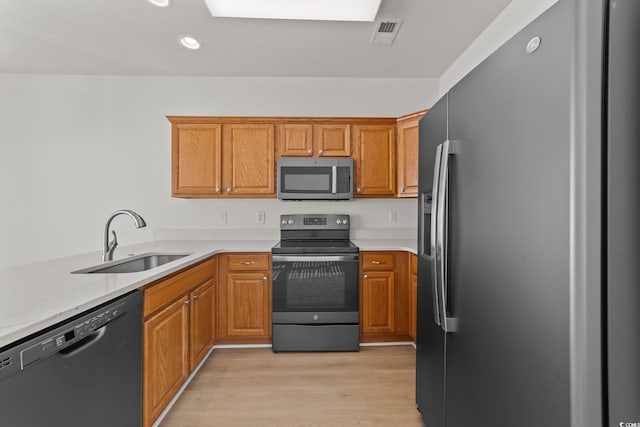 kitchen with light wood-type flooring, sink, light stone countertops, and black appliances