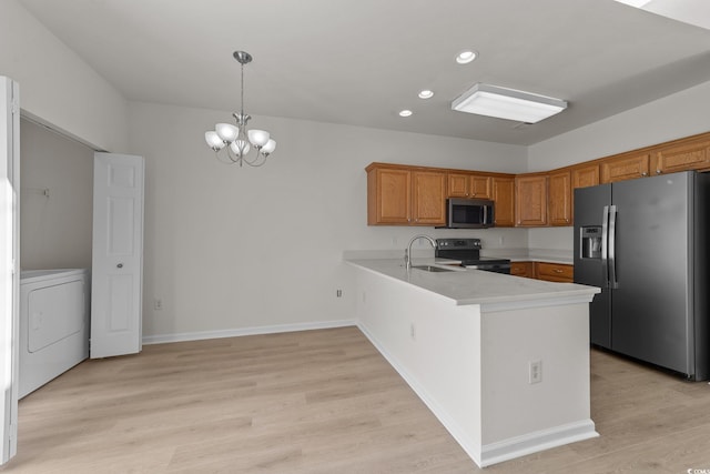 kitchen featuring hanging light fixtures, a chandelier, washer / dryer, appliances with stainless steel finishes, and light wood-type flooring