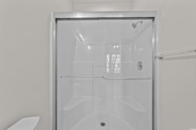 bathroom featuring toilet and a shower with shower door