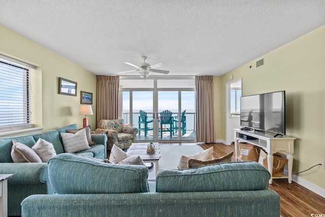 living room with a textured ceiling, dark hardwood / wood-style flooring, and ceiling fan