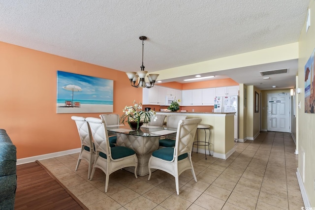 dining space with a notable chandelier, light tile patterned floors, and a textured ceiling