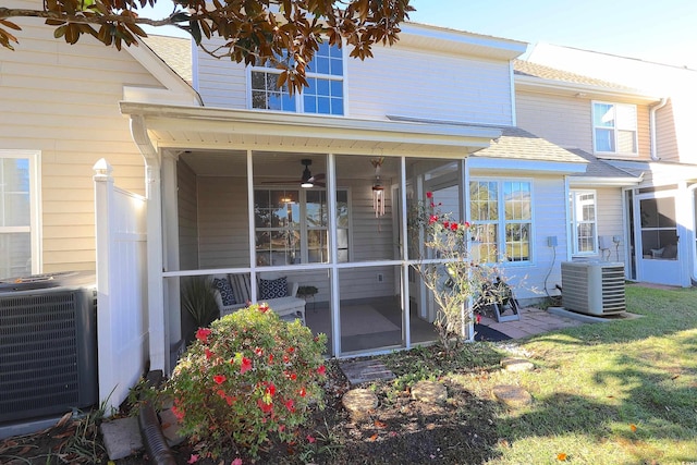 back of property with a sunroom, a yard, and cooling unit