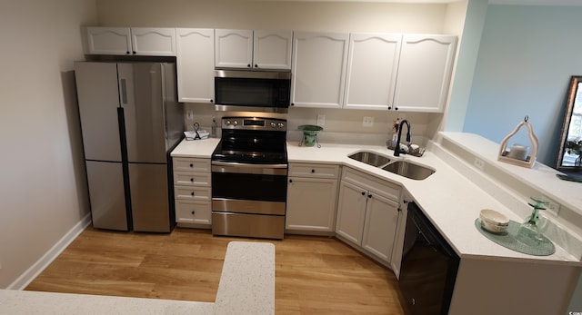 kitchen with white cabinets, stainless steel appliances, light hardwood / wood-style floors, and sink