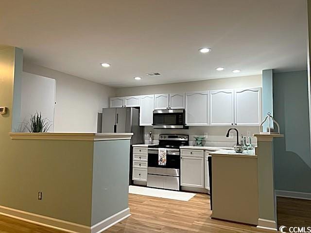 kitchen featuring white cabinets, sink, appliances with stainless steel finishes, and light hardwood / wood-style flooring