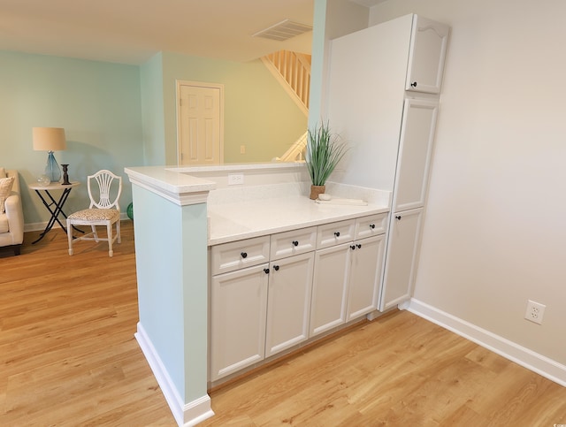 kitchen featuring kitchen peninsula, light wood-type flooring, and white cabinetry