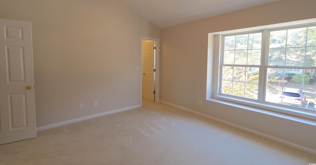 spare room with lofted ceiling, light carpet, and a wealth of natural light