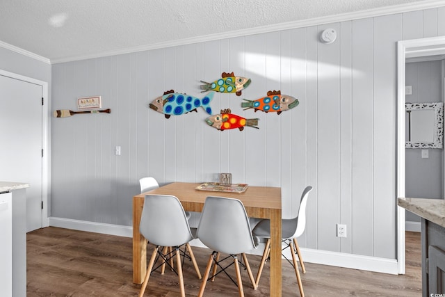 dining area with baseboards, ornamental molding, a textured ceiling, and wood finished floors
