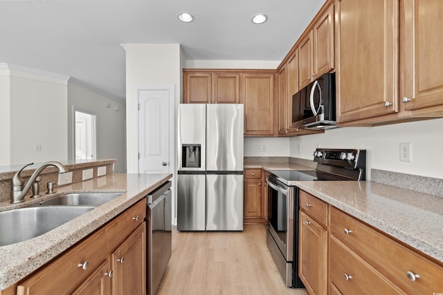 kitchen with crown molding, stainless steel appliances, light stone countertops, and sink