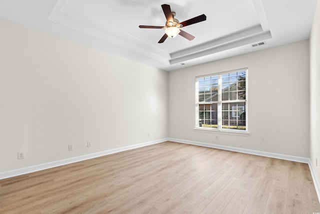 unfurnished room featuring a tray ceiling, light hardwood / wood-style floors, and ceiling fan