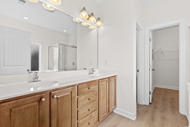 bathroom with wood-type flooring, a shower with shower door, and vanity