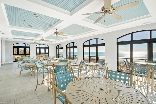 sunroom with coffered ceiling, beamed ceiling, a view of the beach, and a water view