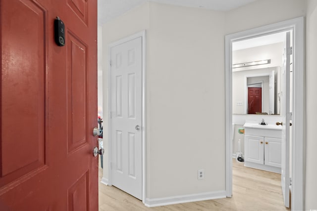 hallway with light hardwood / wood-style flooring and sink