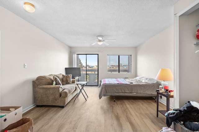 bedroom with ceiling fan, light hardwood / wood-style floors, and a textured ceiling