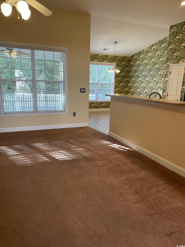 carpeted empty room with ceiling fan with notable chandelier and a wealth of natural light