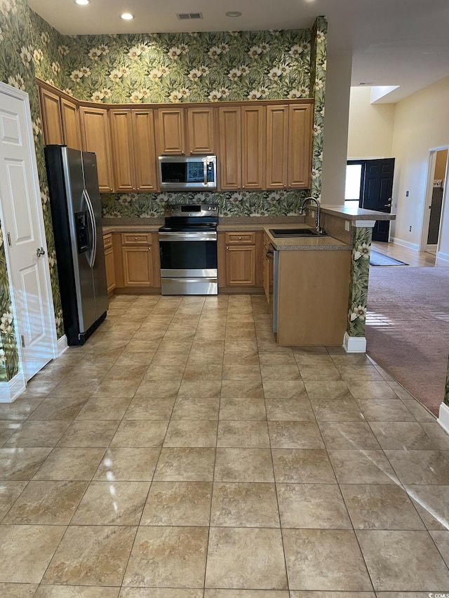 kitchen featuring kitchen peninsula, stainless steel appliances, tasteful backsplash, and sink