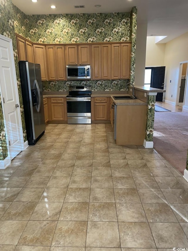 323 Sea Turtle Dr, Myrtle Beach, SC 29588 - kitchen with stainless steel appliances, a sink, a peninsula, tasteful backsplash, and wallpapered walls
