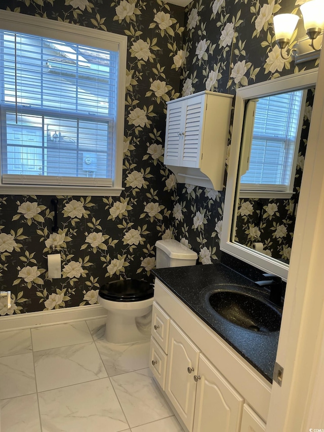 bathroom with an inviting chandelier, vanity, and toilet