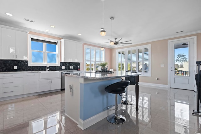 338 Harbour View Dr, Myrtle Beach, SC 29579 - kitchen with dishwasher, crown molding, a center island, baseboards, and a kitchen breakfast bar