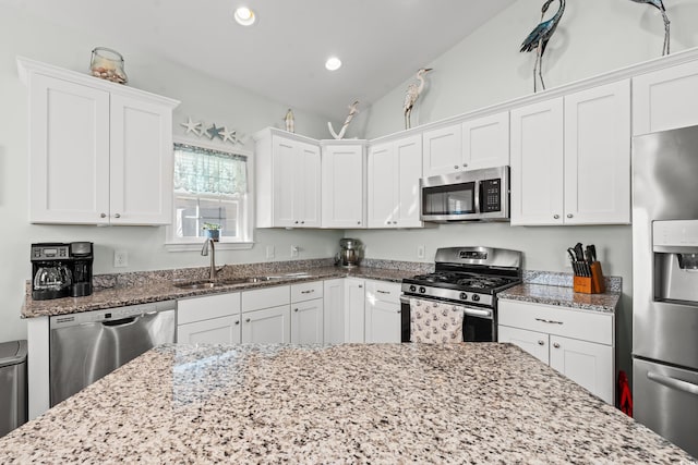 kitchen with white cabinets, stainless steel appliances, and vaulted ceiling