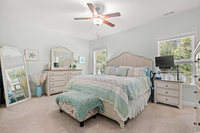 bedroom featuring light colored carpet, multiple windows, and ceiling fan