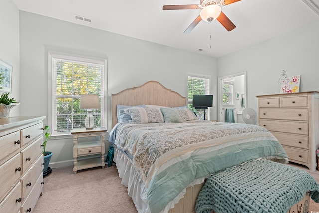 carpeted bedroom featuring multiple windows and ceiling fan