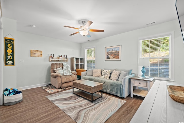 living room with dark hardwood / wood-style flooring, ceiling fan, and plenty of natural light