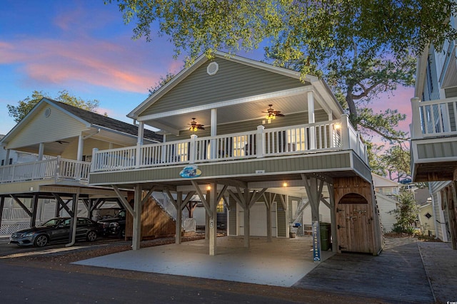 back house at dusk with a carport and ceiling fan