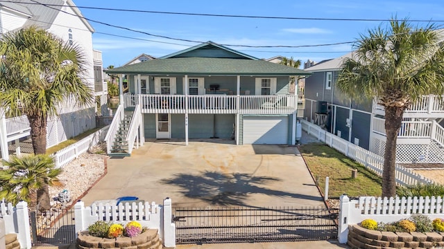 310 34th Ave N, North Myrtle Beach, SC 29582 - coastal home featuring concrete driveway, a fenced front yard, stairs, a gate, and covered porch