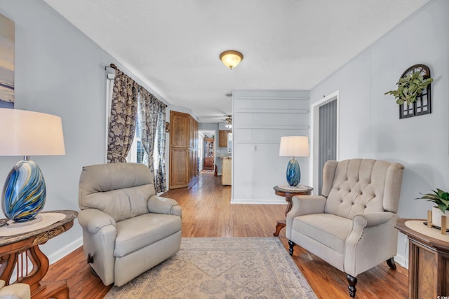 living room with hardwood / wood-style flooring, ceiling fan, and crown molding