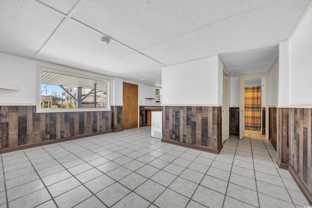 interior space with light tile patterned floors and wood walls