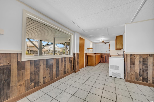 kitchen featuring light tile patterned floors, a textured ceiling, and wooden walls