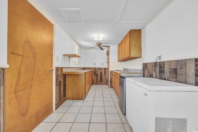 kitchen featuring refrigerator, ceiling fan, wooden walls, sink, and light tile patterned floors