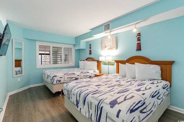 bedroom featuring rail lighting and dark hardwood / wood-style floors