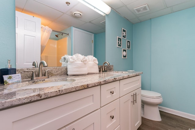 bathroom with a drop ceiling, a shower with curtain, vanity, hardwood / wood-style flooring, and toilet