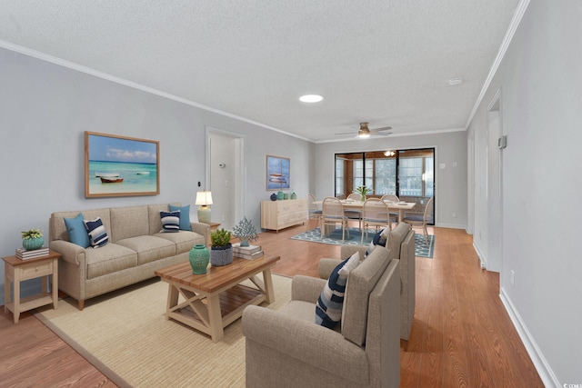 living room featuring light hardwood / wood-style flooring, ceiling fan, and crown molding