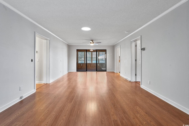 empty room featuring a textured ceiling, hardwood / wood-style flooring, ceiling fan, and crown molding