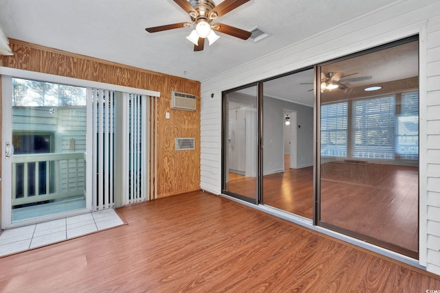 interior space featuring a wall mounted AC, wood walls, ceiling fan, and hardwood / wood-style flooring