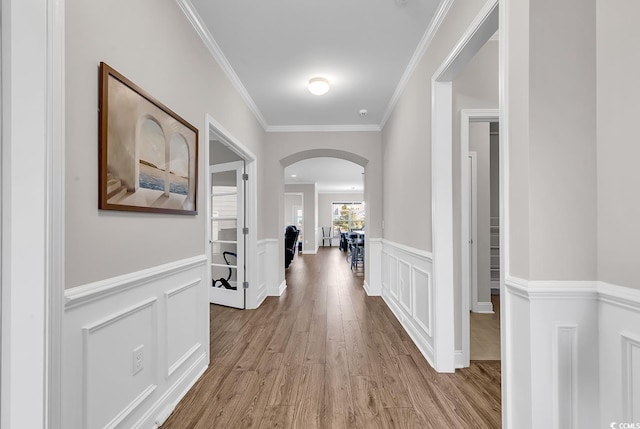 corridor with light wood-type flooring and crown molding